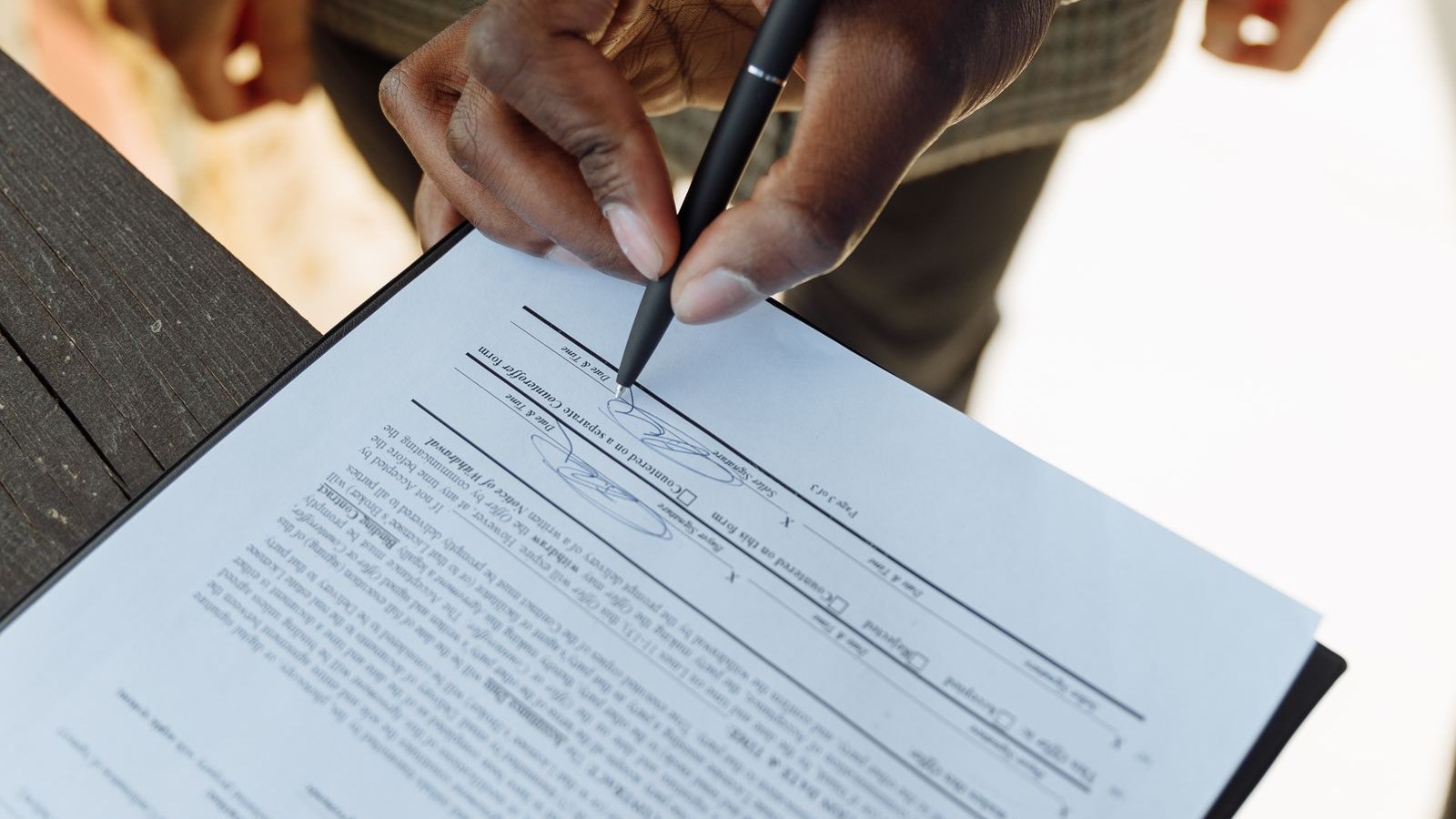 A two-page offer letter on a kitchen table with a pen resting on it