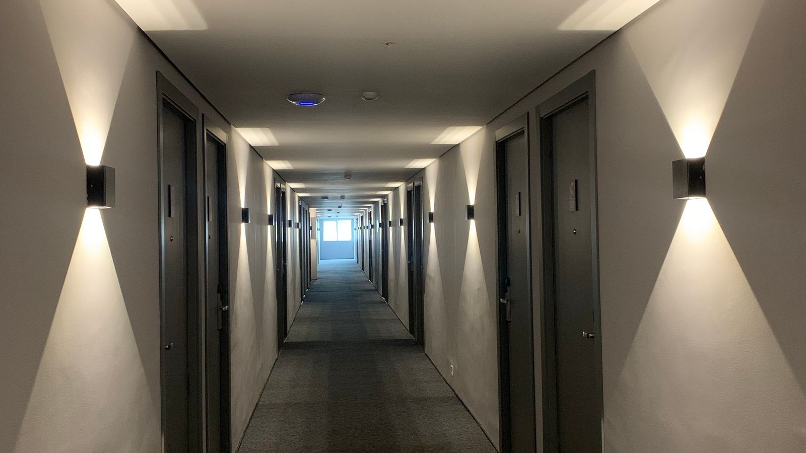 A housekeeping cart parked in a quiet hotel corridor beside an open room door