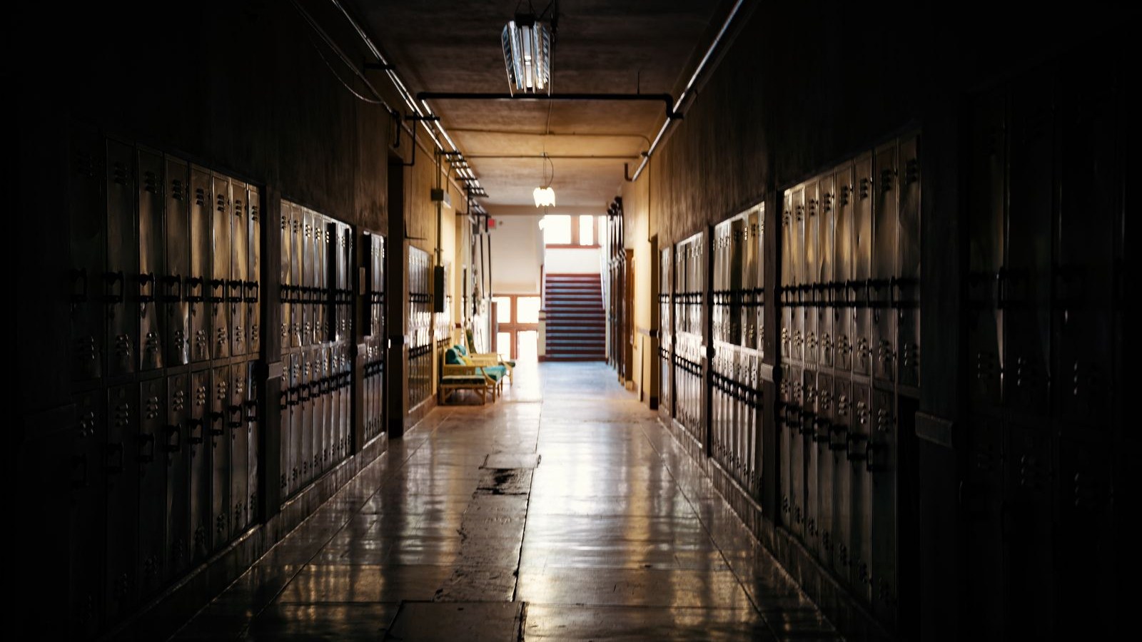 An empty school hallway early in the morning with a cleaning cart parked outside a classroom door