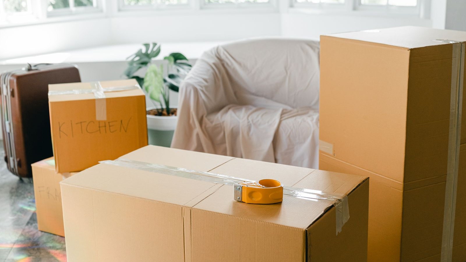 A half-packed moving box on a kitchen counter beside an open laptop