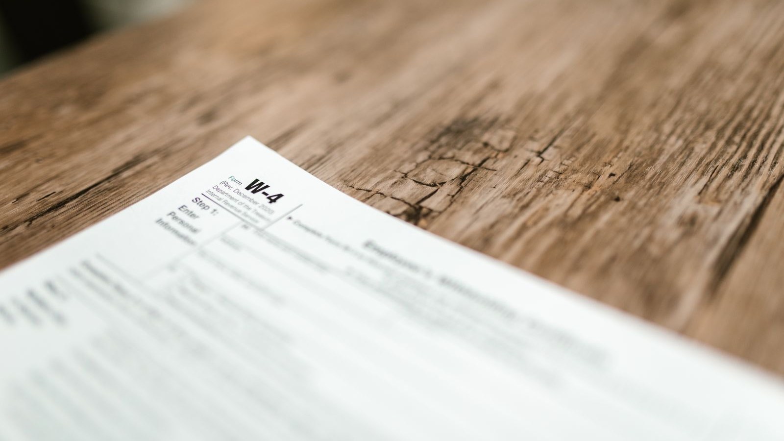A printed paystub on a kitchen counter next to a phone and a cup of coffee